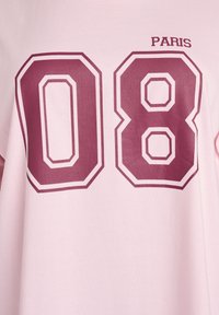 Svetloružové tričko s nápisom "PARIS" a číslom "08" v bordovej farbe, s výrazným atletickým štýlom a ohraničenými detailmi.