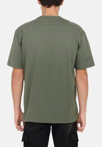 Olivegrünes Baumwoll-T-Shirt mit kurzen Ärmeln, Rundhalsausschnitt und lockerem Schnitt. Die Rückseite ist schlicht und hat keine Grafiken oder Muster.