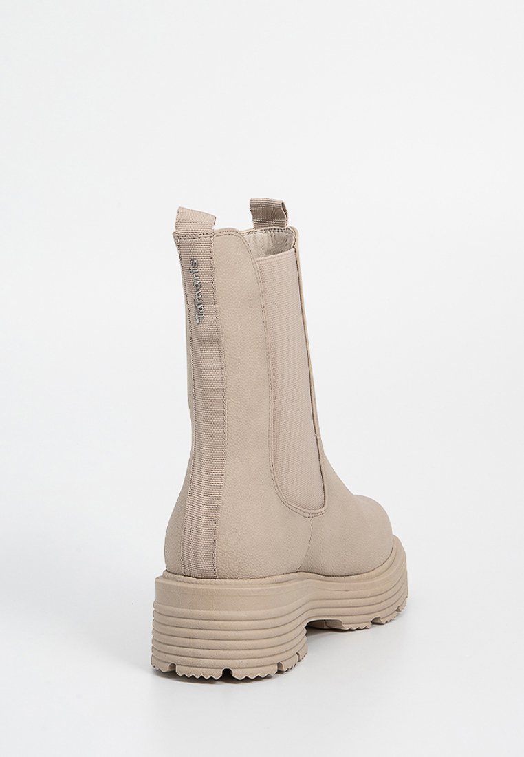 Beige Knöchelschäfte mit elastischen Seitenpaneelen, einer strukturierten Oberfläche und einer grob profilierten Sohle. Verfügt über einen Zugriemen für ein einfaches An- und Ausziehen.