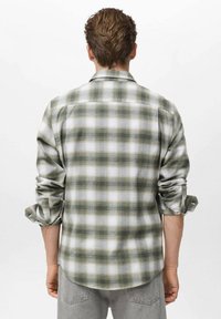 Camisa de franela a cuadros verdes y blancos con mangas enrolladas, corte recto, cuello abotonado y textura de tela visible. Se muestra la vista trasera.