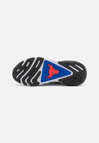 En sort-hvid sportsko sål med et blåt og rødt trekantsdesign og et tyre-logo, med struktureret sål for greb.