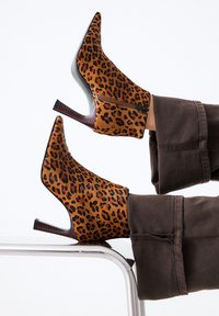 Botines de estampado de leopardo hechos de un material suave, con punta afilada y tacón alto, y cremallera lateral para un fácil uso.