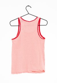Canottiera a righe rosse e bianche con colletto tondo e ampie aperture per le braccia, con bordi rifiniti in rosso, appesa a un gancio nero.