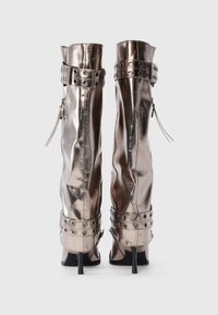 Cizme metalice argintii până la genunchi, cu un design elegant, din piele texturată, fermoare laterale și curele la gleznă cu studuri. Tocuri stileto.