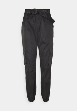 Mustat kuorihousut, joissa on teksturoitu kangas. Ominaisuuksiin kuuluu säädettävä vyö, sivutaskut ja joustavat lahkeensuut.