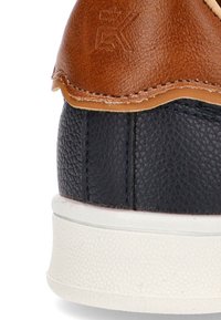 Zapatillas de cuero marrón y negro con un acabado texturizado, acentos cosidos y una suela de goma blanca. Logotipo grabado en la parte marrón.