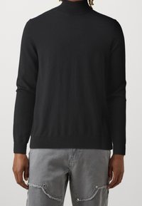 Czarny golf z długimi rękawami, prążkowanym kołnierzem i mankietami, wykonany z miękkiej, gładkiej tkaniny, w połączeniu z szarymi spodniami cargo.