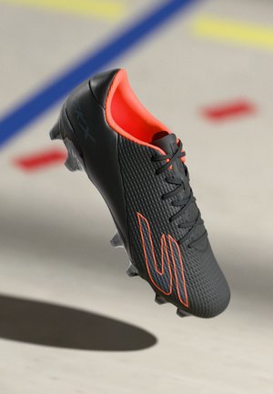 Botas de fútbol negras con parte superior texturizada, acentos en naranja y cordones. Presenta un diseño aerodinámico y una suela moldeada para tracción.