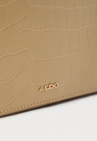 Bež denarnica iz umetnega krokodilskega usnja, s teksturirano površino in zlatim logotipom "ALDO", z diskretnim šivanjem ob robovih.