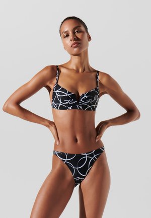 Set di bikini nero con bralette decorata con linee astratte bianche e slip a vita bassa abbinati. Tessuto morbido con spalline regolabili.