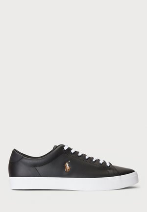 Zapatilla de cuero negra con suela blanca, que presenta cordones en contraste y un pequeño logotipo bordado en el costado. Acabado suave, diseño de perfil bajo.