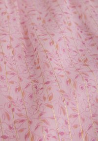 Lichtroze stof met een bloemenpatroon in donkerder roze en oranje tinten, geaccentueerd met dunne gouden strepen. Effen textuur.