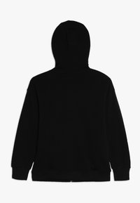 Sudadera negra con una costura central en la parte trasera, una gran capucha y puños acanalados. El material parece suave y texturizado, diseñado para el confort.