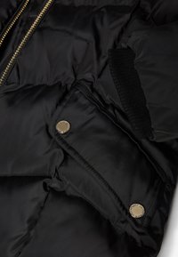 Czarna kurtka puchowa z pikowanym wzorem, złotym zamkiem błyskawicznym i zatrzaskami. Gładki materiał nylonowy z prążkowanym wykończeniem mankietów.