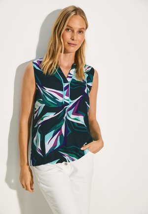 Sleeveless blouse in dark blue with abstract leaf patterns in teal, purple, and white. Collared neckline and relaxed fit, paired with white pants.