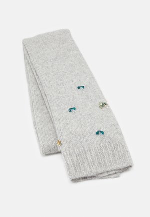 Écharpe tricotée gris clair avec de petites décorations de perles bleues et dorées, pliée sur un fond blanc.
