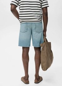 Pantaloni scurți din denim de culoare albastră deschisă, cu un finisaj șters, având buzunare pe spate. Cămașă cu mânecă scurtă, cu dungi alb-negru, purtând o geantă tote maro.