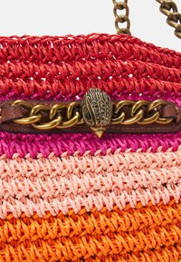 Tkaná kabelka v červené, růžové, broskvové a oranžové barvě s texturovaným vzorem. Obsahuje dekorativní hnědou koženou rukojeť a kovové zapínání.