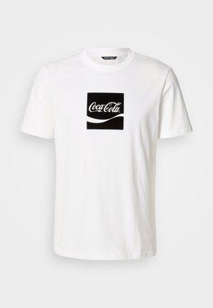 Bela bomba majica iz bombaža, ki ima črn kvadratni grafični vzorec z logotipom Coca-Cole in valovitimi oblikami v belem, kratkimi rokavi in okrogli ovratnik.