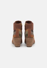 Bottes à la cheville marron avec une tige en textile côtelé, des panneaux latéraux à carreaux et un talon empilé. Comprend des fermetures éclair dorées de chaque côté.