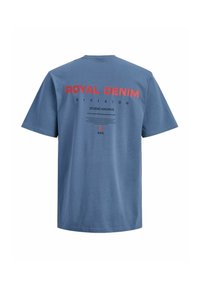 Blaues T-Shirt mit kurzen Ärmeln, mit der Aufschrift "ROYAL DENIM DIVISION" in roter und schwarzer Schrift sowie zusätzlichem kleinerem schwarzem Text "STUDIO ARCHIVE" auf der Rückseite.