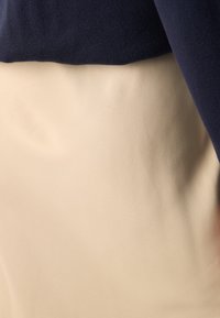 To-lags antrekk med en marineblå strikket topp og et glatt beige skjørt, fremhever kontrasterende farger og myke teksturer.