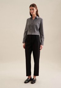 Grå kortærmet slå-om skjorte, sorte plisserede bukser, blanke sorte loafers, glatte stofstrukturer, skræddersyet pasform, minimalistisk design.