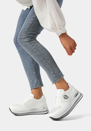 Sneaker atletiche bianche con una tomaia texturizzata, sezione del tallone trasparente, suola a strisce bianche e nere e chiusura con lacci.
