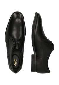 Chaussures habillées en cuir noir avec une finition lisse, bout rond, design à lacets et un petit talon en caoutchouc. Présente des détails de couture subtils.