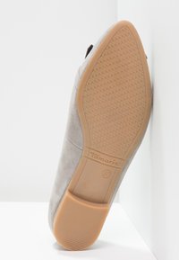 Suela de un zapato gris de ante, con punta afilada, suela de goma texturizada en color marrón y tacón cuadrado, talla 37, de la marca "Tamaris."