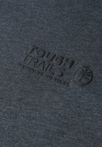 Tmavě modrá bavlněná látka s vyraženým černým logem "TOUGH TRAILS" a kruhovým znakem stromu. Měkká textura, minimální vzor.