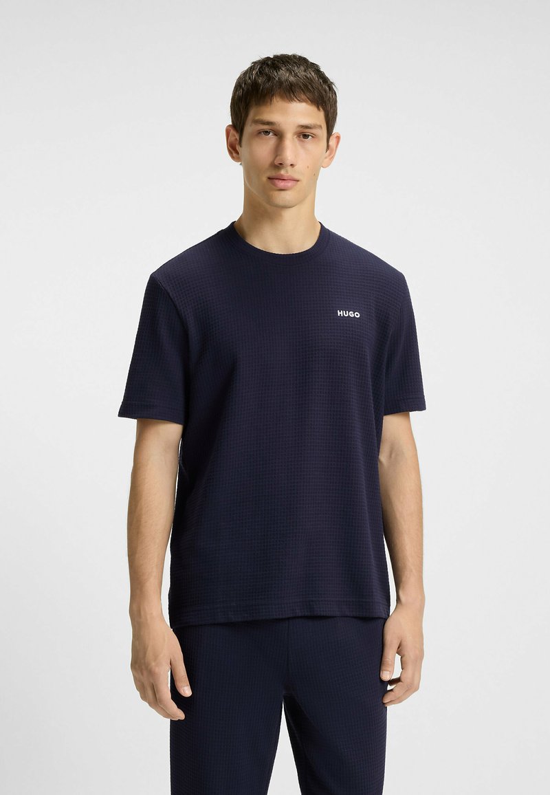 T-shirt blu navy a maniche corte con un motivo strutturato e scollatura rotonda. Presenta un piccolo logo bianco "HUGO" sul petto.