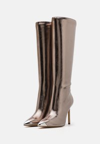 Stivali alti metallici fino al ginocchio in rosa oro con una texture liscia, punta affusolata e dettagli cromati sulla punta. Design con tacco a stiletto.