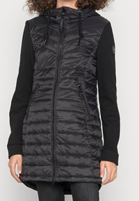 Gilet nero con zip frontale, cappuccio e maniche lunghe nere. Presenta una texture trapuntata e tasche laterali con zip.