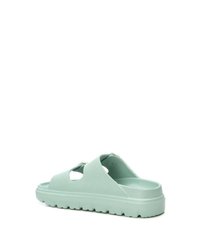 Chanclas de color verde claro con un diseño abierto, que cuentan con detalles recortados, una suela gruesa y un fondo texturizado para mayor agarre.