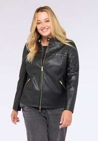 Svart läderjacka med dragkedja fram, hög krage och sidfickor. Har detaljer i guld och en figursydd design. Slät textur.