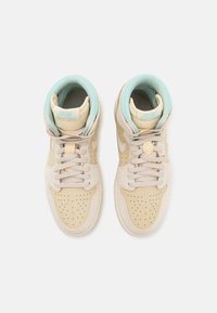 Sneakers alte beige con design perforato, camoscio testurizzato e accenti blu chiaro sul collare e sulla linguetta. Visibili lacci e interno imbottito.