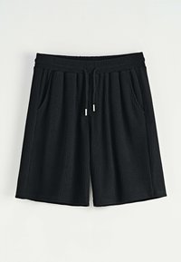 Shorts noirs à côtes avec une taille élastique, un système de fermeture à cordon de serrage, et deux poches latérales. Texture lisse avec une coupe décontractée et jambes larges.