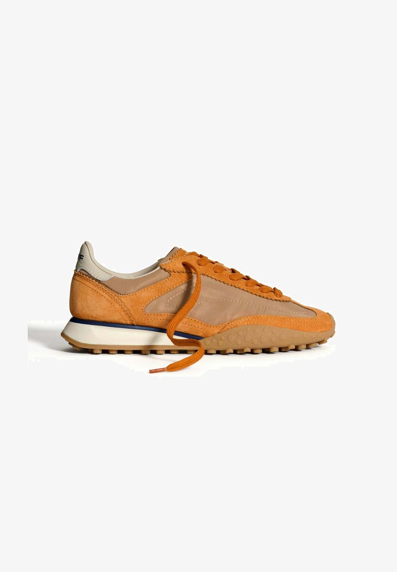 Zapatillas en color naranja y beige, hechas de cuero y malla, con punta redondeada, acentos texturizados y suela de goma blanca con tacos de tracción.