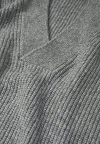 Grau geripptes Strickstoff mit sichtbaren Texturdétails und einer aufgesetzten Tasche, weich im Aussehen und mit gleichmäßigem Strickmuster.