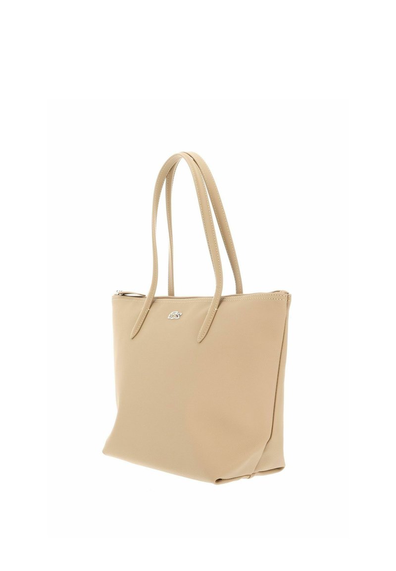 Beige leather tote bag with two long handles and a small silver logo on the front, shown on a white background.