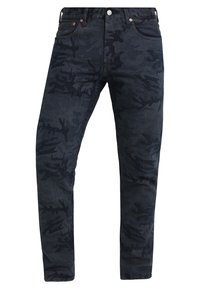 Mörka camo-jeans i denimtyg. Har en tajt passform, subtil textur och koppardetaljer vid midjan och fickorna.