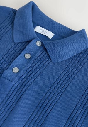 Kék kötött galléros póló texturált, függőleges csíkokkal, három szürke gombbal és egy „next” márkajelzéssel a gallér belsejében.