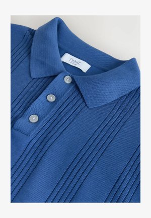 Sinine kootud polo särk tekstuursete vertikaalsete triipudega, kolm halli nööpi ja "next" kaubamärgiga sildiga krae sees.