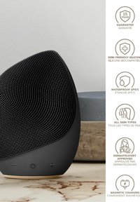 Sort silikonhøjttaler med en struktureret overflade og ergonomisk design. Funktioner inkluderer vandtæthed (IPX7) og magnetisk opladning.