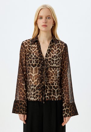 Blusa in tessuto trasparente con stampa leopardata, caratterizzata da un nodo frontale, maniche lunghe con polsini svasati e colletto. Toni terrosi con accenti a contrasto.