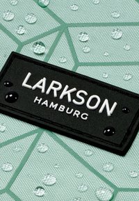 Green textured fabric with a geometric pattern, featuring water droplets. A rectangular black label displays "LARKSON" and "HAMBURG" in white.
