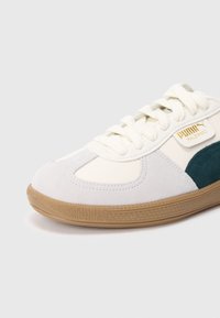 Teniska Puma Palermo v barevném provedení krémové, šedé a zelené barvy, s texturami z semiše a hladké kůže a podrážkou z gumové pryže. Zlatý detail s logem.