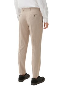 Beige broek met een gestructureerde afwerking, slim fit, twee achterzakken en knoopaccenten. Gestyled met zwarte sneakers.