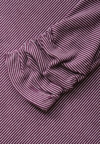 Paarse en witte gestreepte stof met een gathered cuff-ontwerp en een zachte textuur. De strepen zijn gelijkmatig verdeeld en duidelijk.